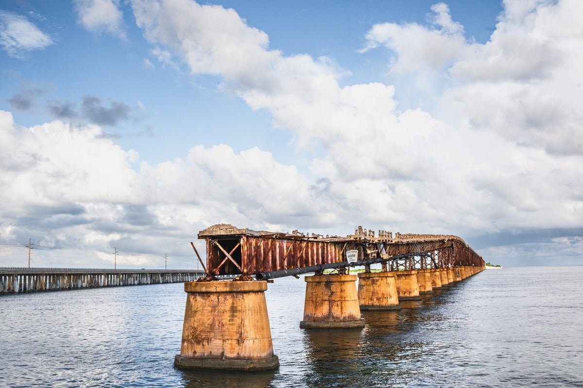 Weathered Old Bahia Honda Rail Bridge stretching over coastal water beneath a cloudy Florida Keys sky.