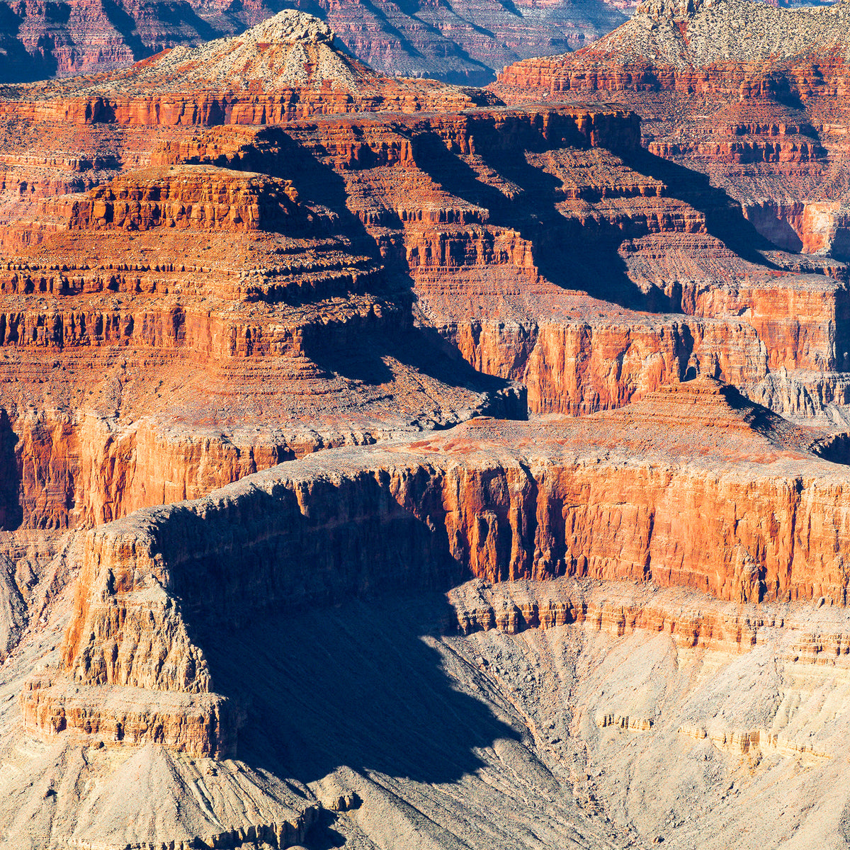 Sunlit layers of sandstone mesas and buttes casting deep shadows across the Grand Canyon in Arizona.