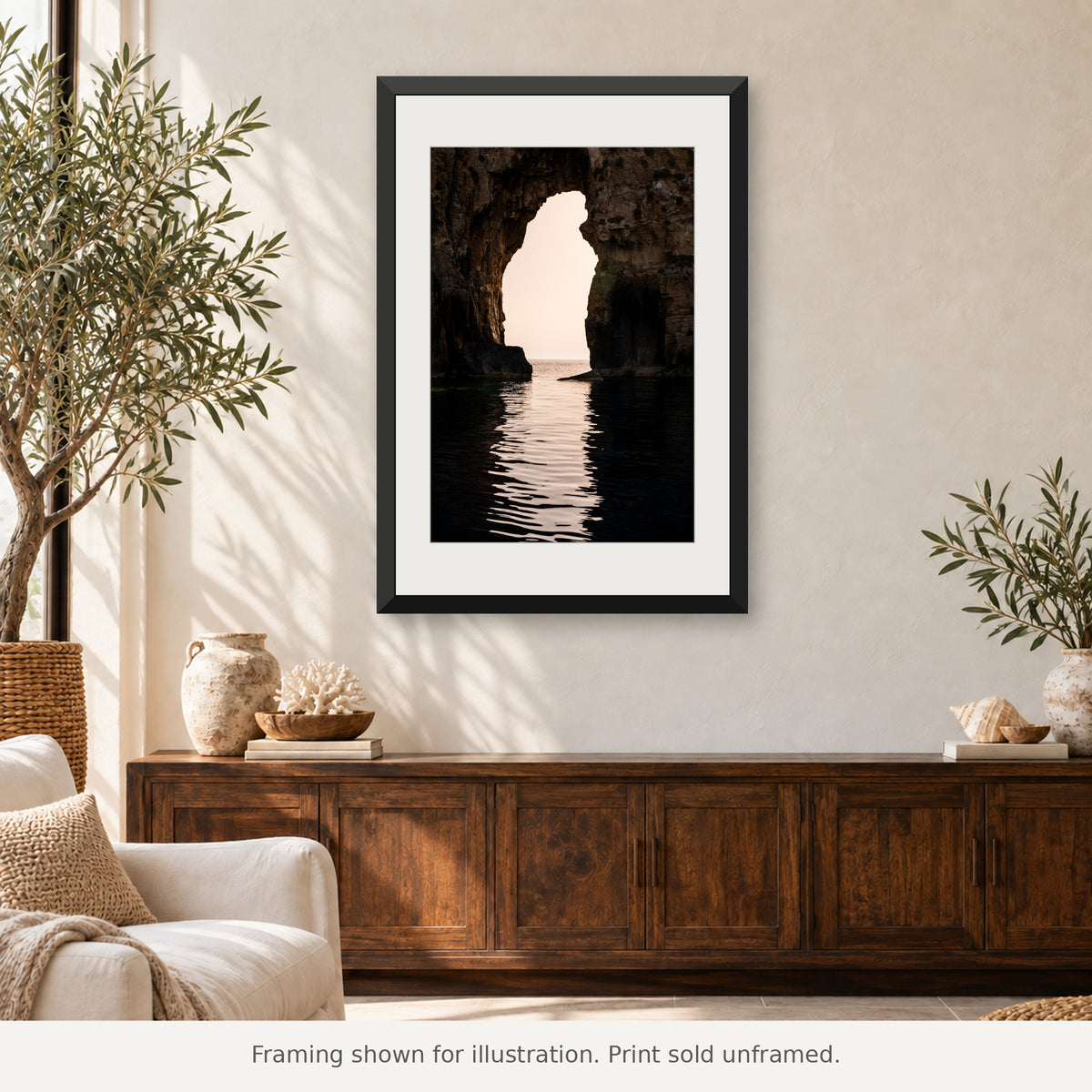 Framed Navarino Sea Arch photograph above a wooden console in a Mediterranean interior with olive plants. Print sold unframed.