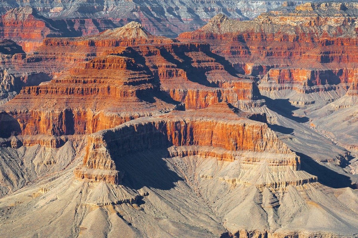 Layered red and pale rock formations with deep shadows in the Grand Canyon, Arizona.