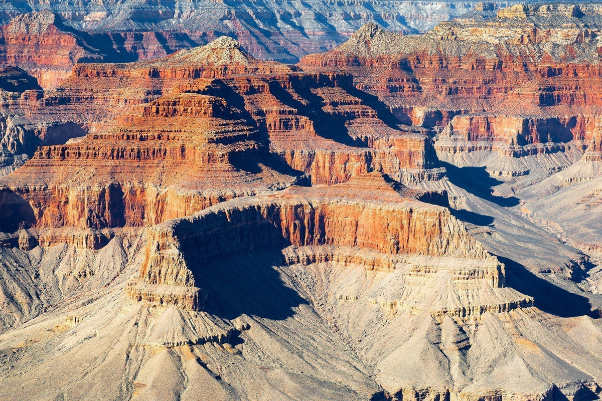 Sunlit layers of sandstone mesas and buttes casting deep shadows across the Grand Canyon in Arizona.