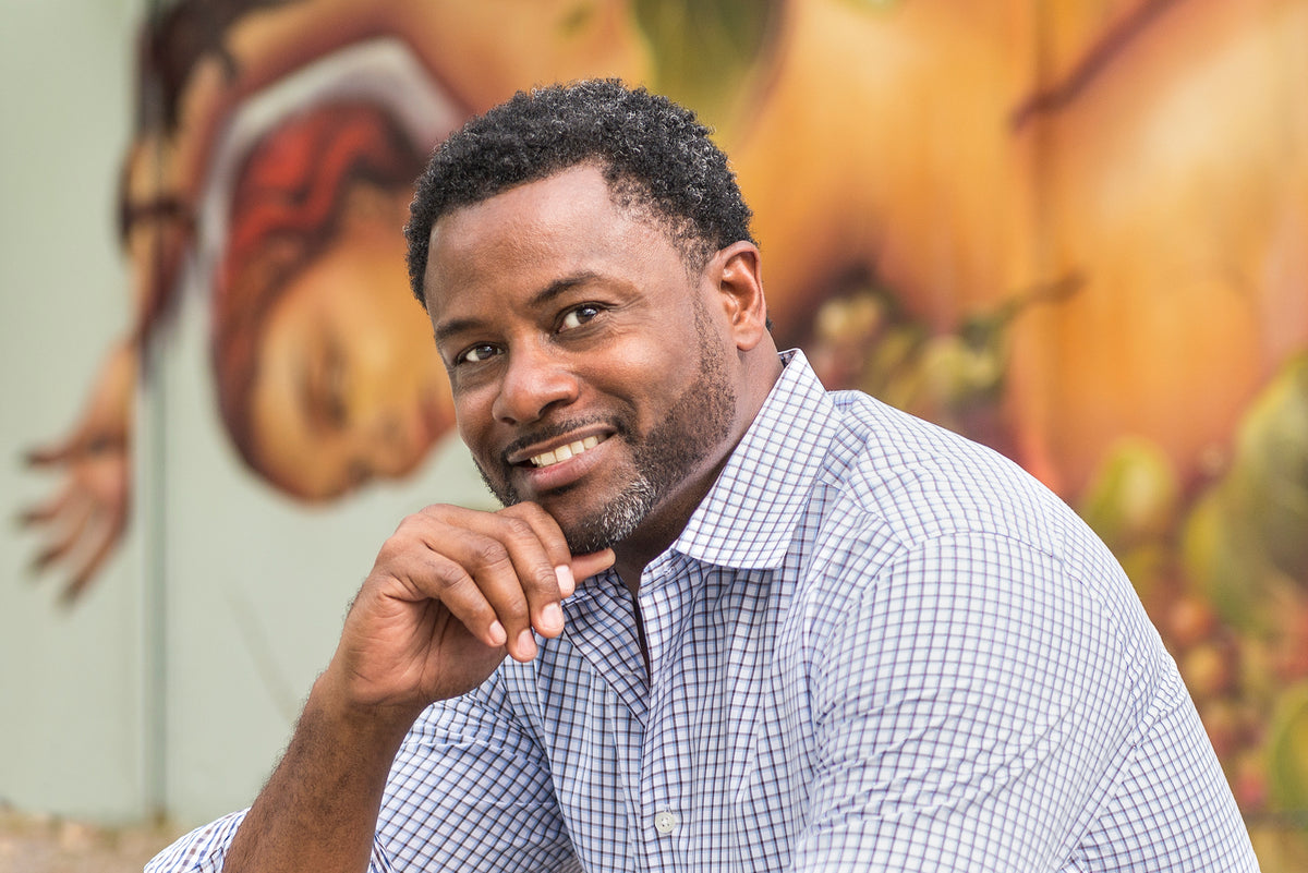 Fine art photographer Antonio Crutchley smiling in front of a colorful mural at Wynwood Walls in Miami.