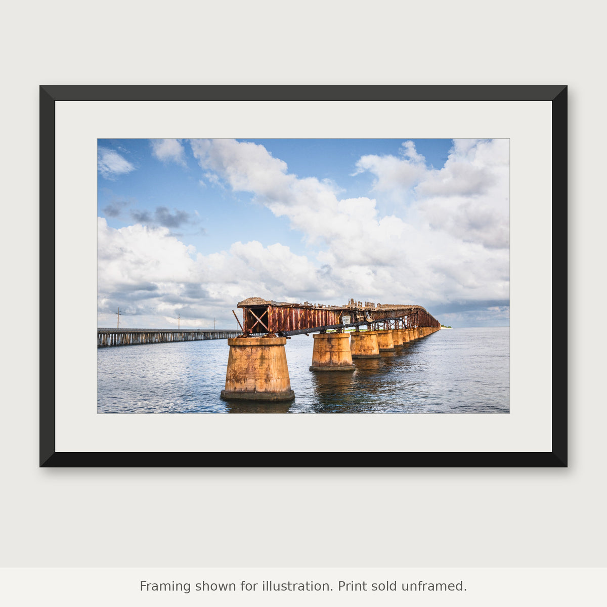 Weathered Old Bahia Honda Rail Bridge stretching over coastal water beneath a cloudy Florida Keys sky. Print sold unframed.