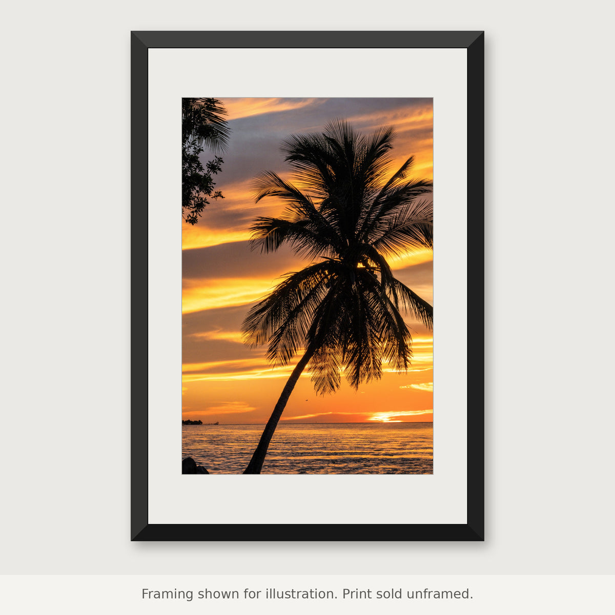 Lone palm tree silhouetted against glowing orange and pink sunset clouds in the Florida Keys. Print sold unframed.