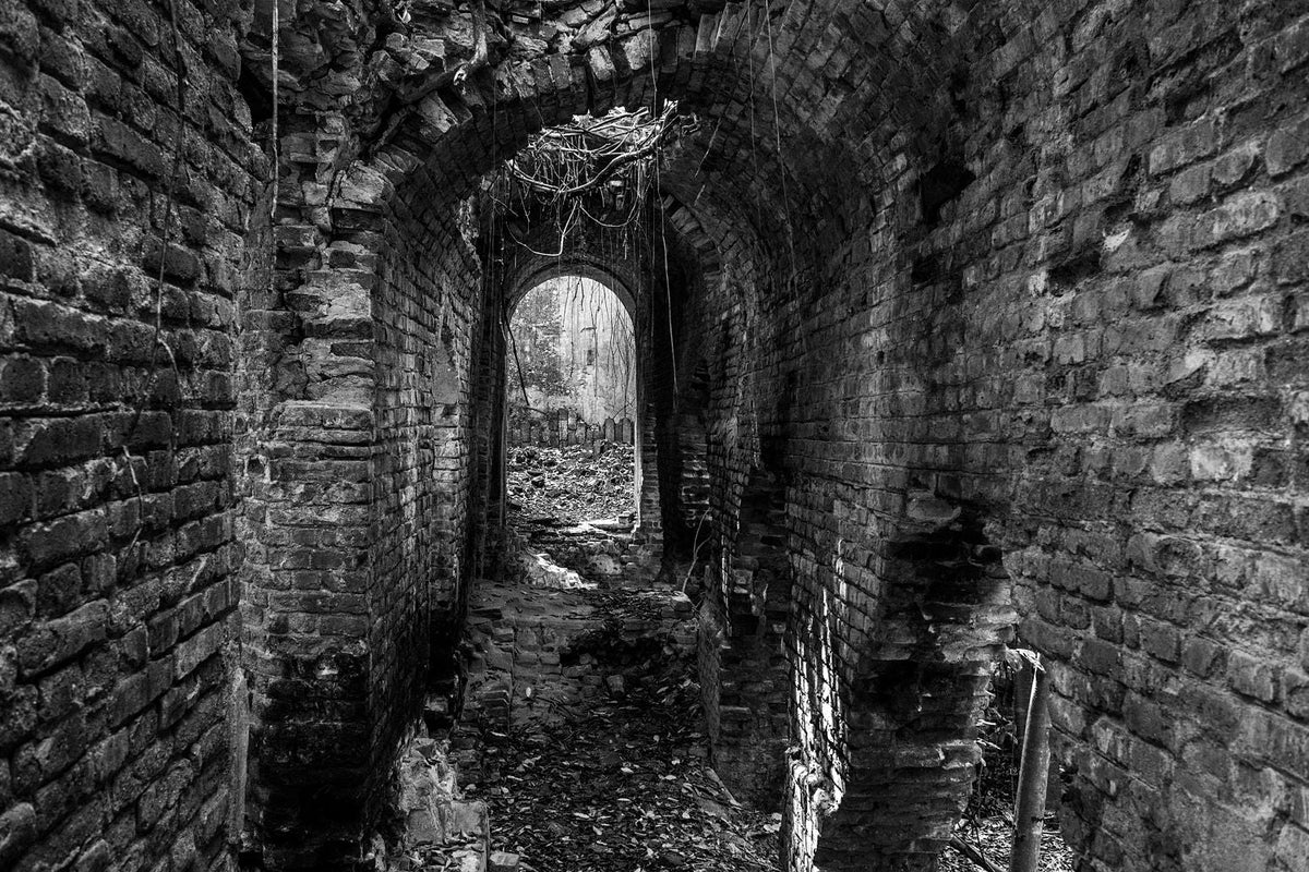 Black-and-white photograph of an arched brick passage within the Central Playa Grande ruins in Vieques, Puerto Rico.
