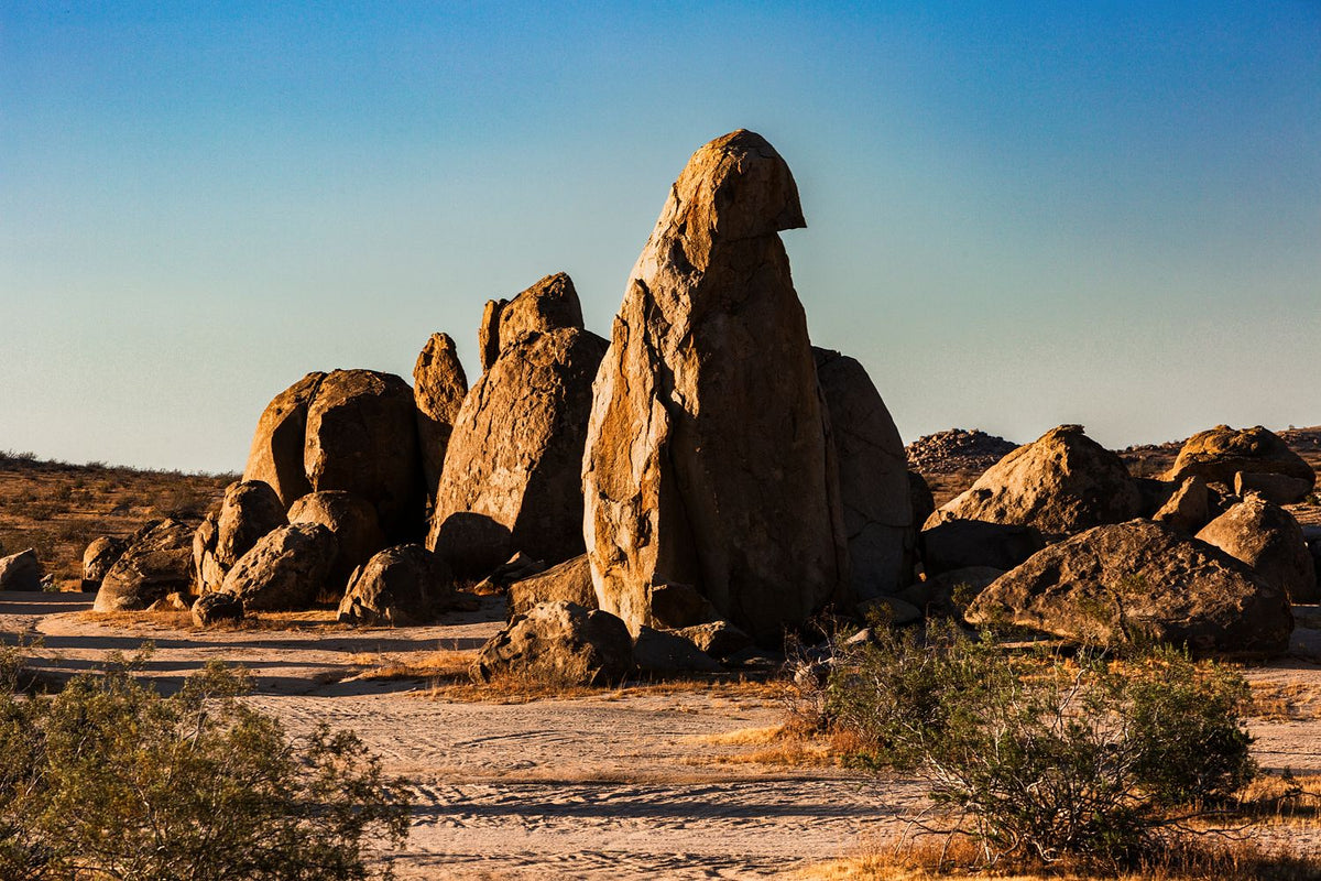 Tall rounded desert boulders illuminated by golden light, with long shadows across the foreground.