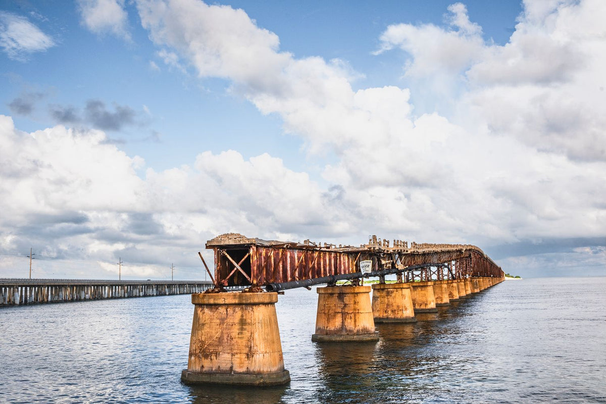 Weathered Old Bahia Honda Rail Bridge stretching over coastal water beneath a cloudy Florida Keys sky.
