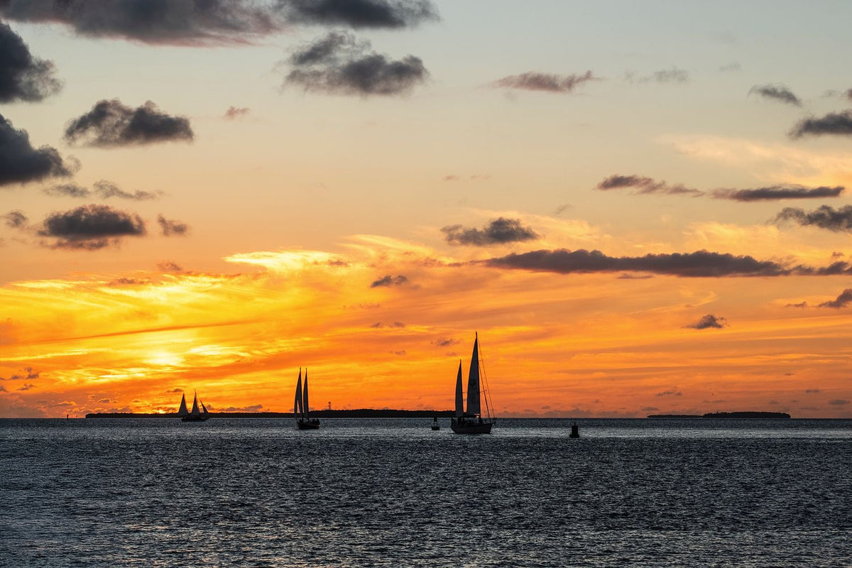 Sailboats silhouetted against a glowing sunset over the water in Key West, Florida.